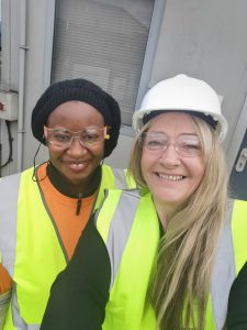 two women smiling at the camera with hard hat and high visibility jackets